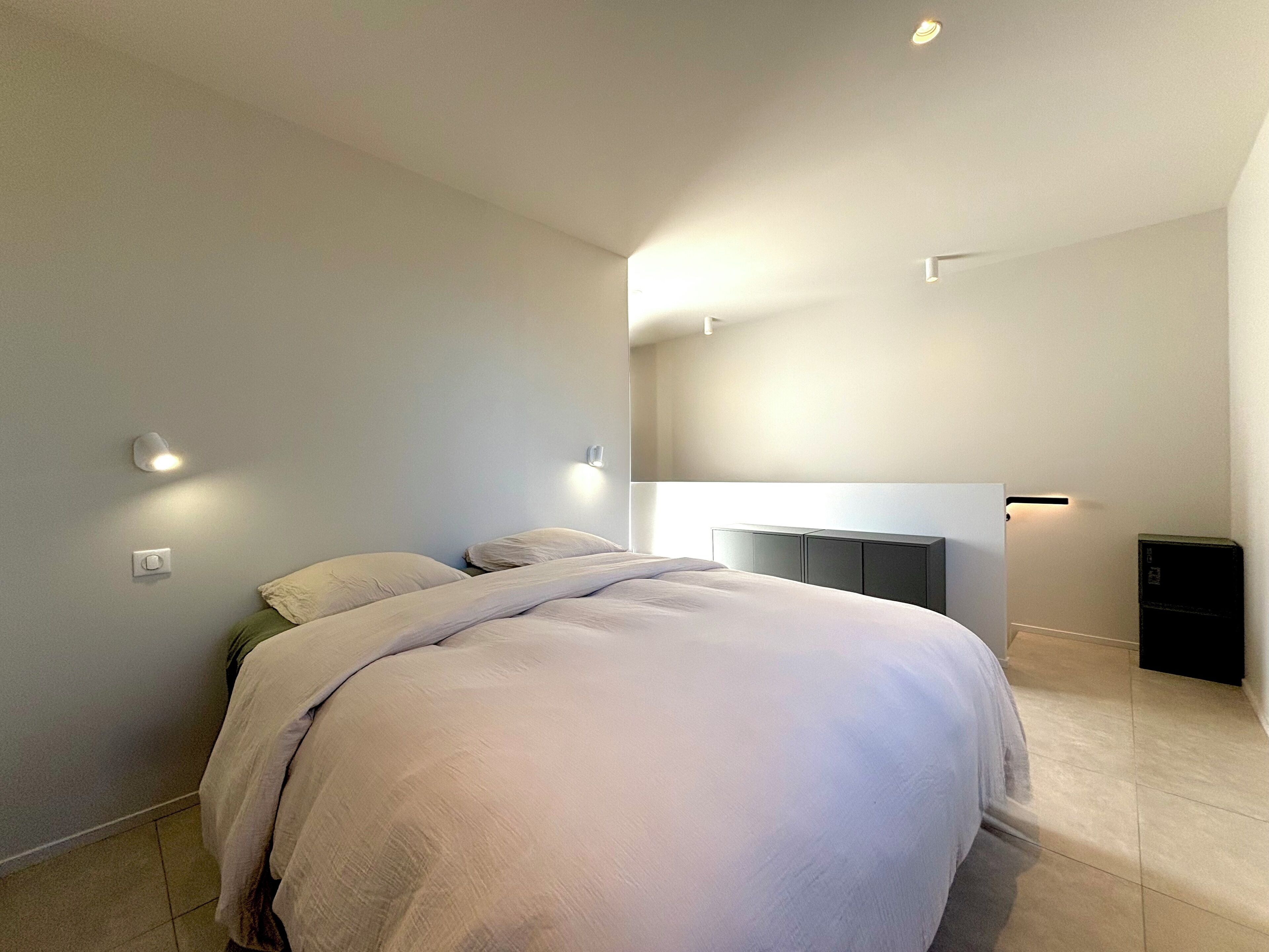 Un dormitorio moderno con una cama grande, una mesita de noche y un armario empotrado.