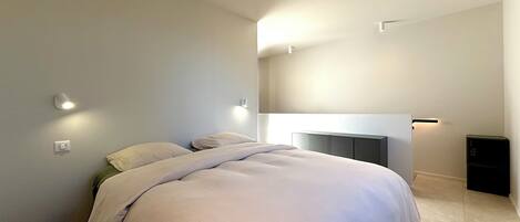 Un dormitorio moderno con una cama grande, una mesita de noche y un armario empotrado.