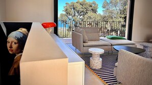 Ein modernes Wohnzimmer mit Sofa, Couchtisch und Blick auf einen Balkon mit Bäumen.