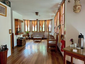 A room with wooden flooring, a sofa, chairs, a table with a kettle, and a fire extinguisher. - Tierra Viva Ollantaytambo (Ollantaytambo)