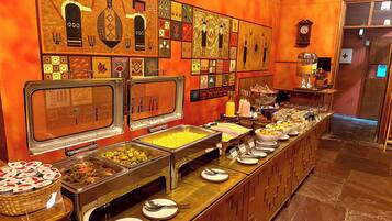 Un bufé con diversas opciones de comida, un reloj y una pared decorada con arte cultural.