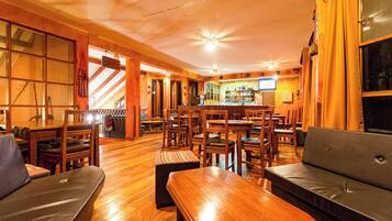 Un restaurante acogedor con mobiliario de madera, una zona de bar y una chimenea.