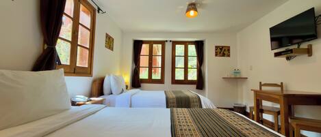 A hotel room with two beds, a desk, a chair, a television, and a ceiling light.
