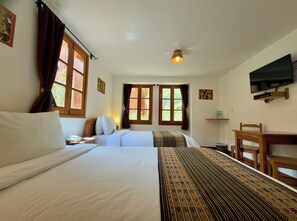 A hotel room with two beds, a desk, a chair, a television, and a ceiling light. - Tierra Viva Ollantaytambo (Ollantaytambo)
