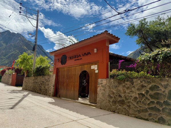 A hotel entrance with a wooden door, stone walls, and a mountain backdrop. - Tierra Viva Ollantaytambo (Ollantaytambo)