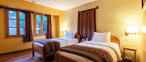 Une chambre d’hôtel avec deux lits en bois, un plancher en bois et une fenêtre avec des rideaux.