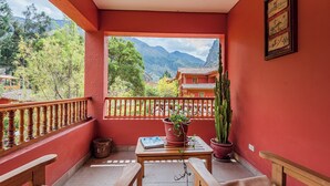 Un balcon avec une table en bois, deux chaises, une plante en pot et un cactus.