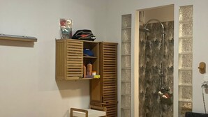 A bedroom with a bed, a ceiling fan, a wardrobe, a shower area, and a small shelf with toiletries. - Two rooms 300 m from beach and town center (Sainte-Anne)