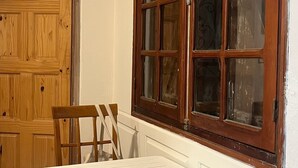A room with a wooden door, a window with multiple panes, a white table, and two wooden chairs. - Two rooms 300 m from beach and town center (Sainte-Anne)