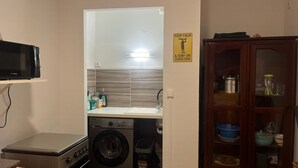 A compact kitchen with a washing machine, a microwave, and a cabinet with kitchenware. - Two rooms 300 m from beach and town center (Sainte-Anne)