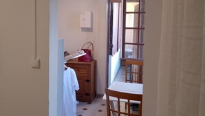 A narrow hallway with a wooden chair and a small table, a wooden cabinet, and a red bag on the floor. - Two rooms 300 m from beach and town center (Sainte-Anne)