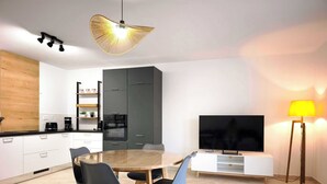Una cocina moderna con comedor, televisor y lámpara.