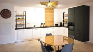 Una cocina moderna con armarios blancos, una mesa de comedor de madera y una lámpara colgante.