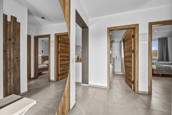 A modern interior with wooden doors, a kitchen area, and a bathroom visible through the doors. - Oliva Serenity Pool Apartment (Pomer)