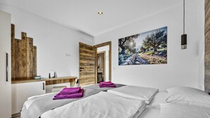 A modern hotel room with two beds, a wooden accent wall, a painting of a landscape, and a desk with a chair. - Lavanda Harmony Apartment (Pomer)