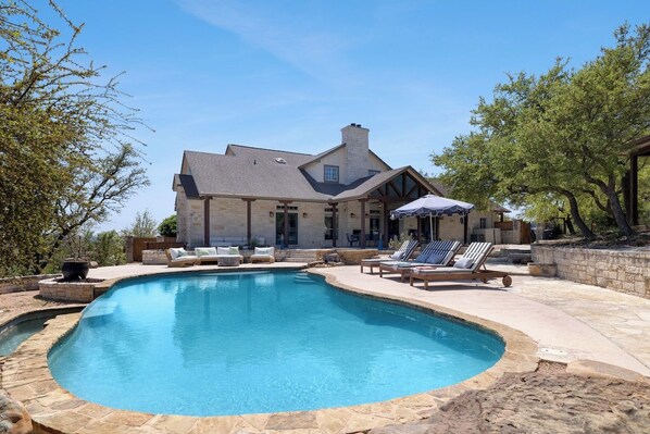 A house with a swimming pool, lounge chairs, and a patio area.