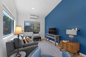 A modern living room with a sofa, a television, a lamp, and a wooden cabinet.