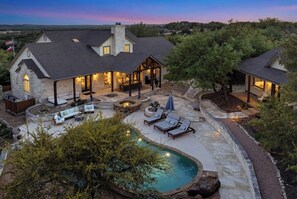 Une grande maison avec une piscine, un espace extérieur aménagé pour s’asseoir et une terrasse couverte.