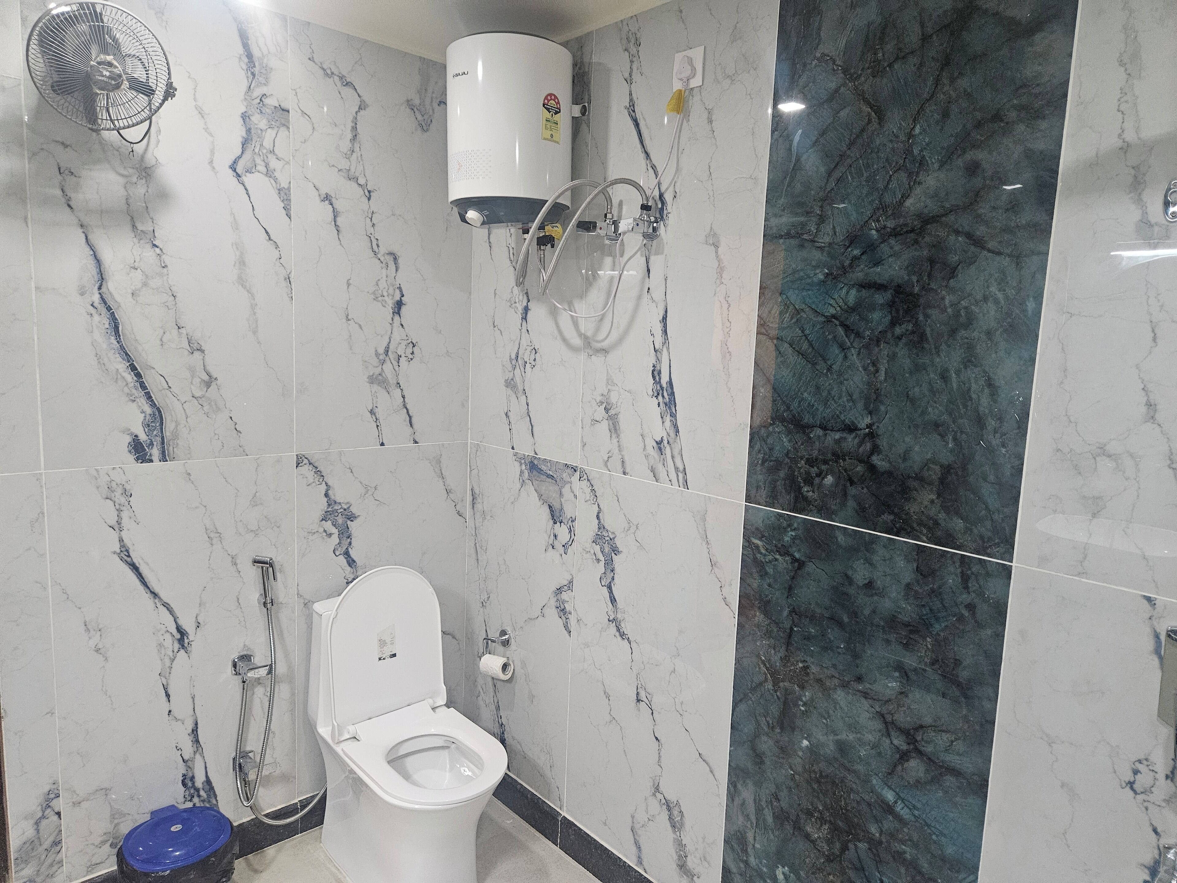 Et badeværelse med toilet, hårtørrer og vandvarmervarmtvandsbeholder.