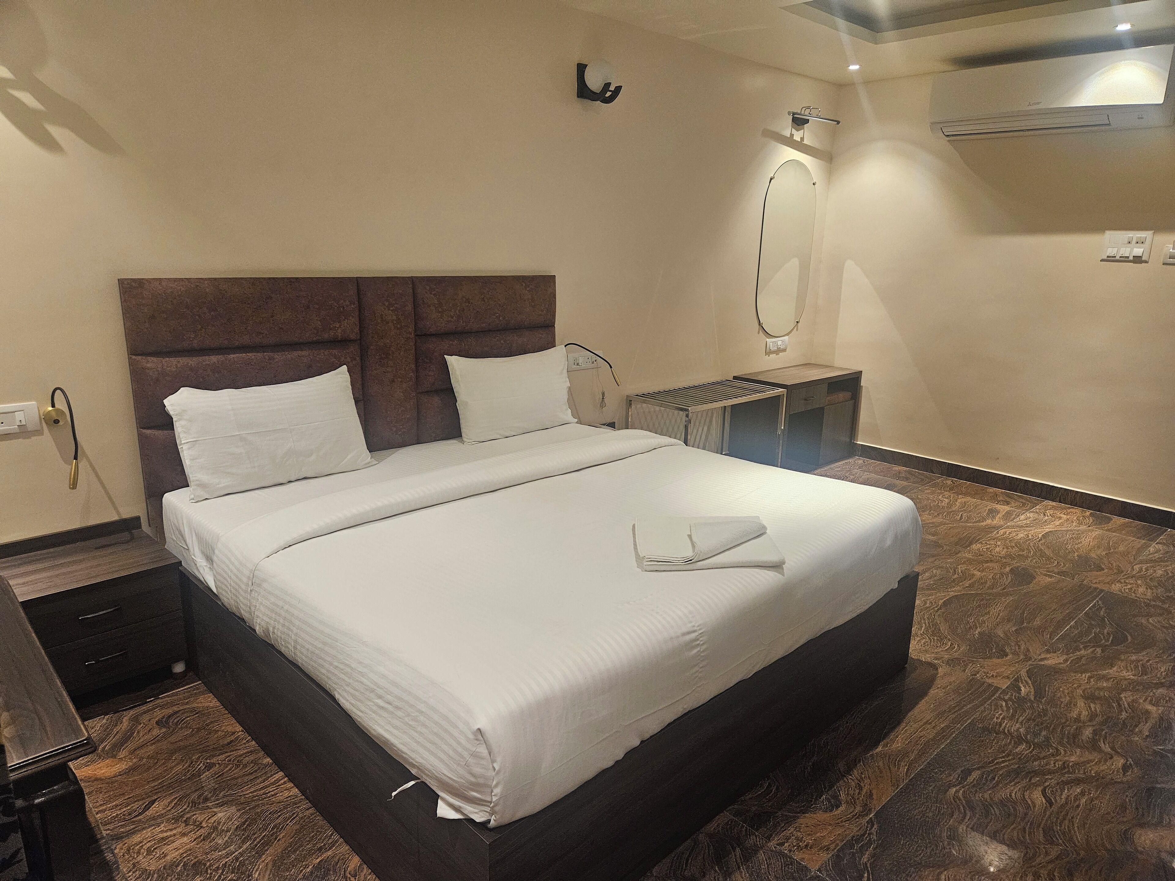 A neatly made bed with white linens, a wooden headboard, and a small bedside table with a lamp.