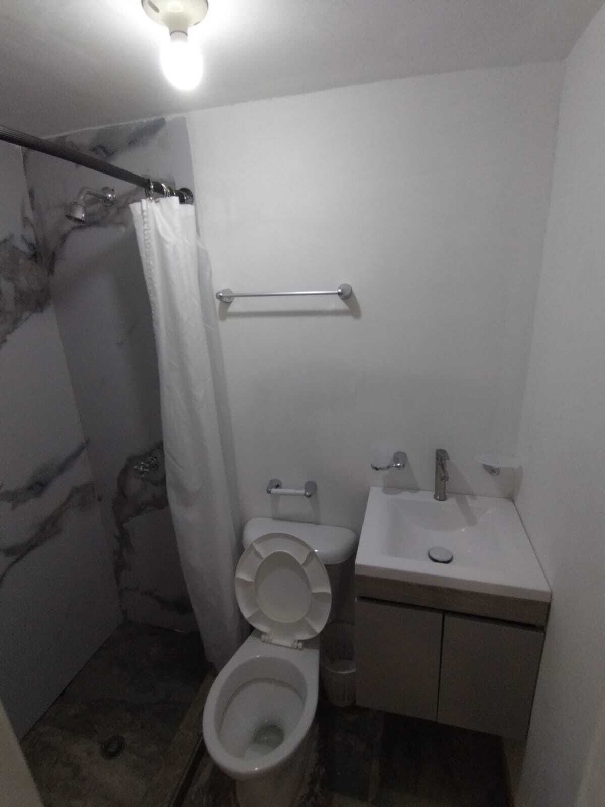 A small, compact bathroom with a toilet, sink, and shower area.