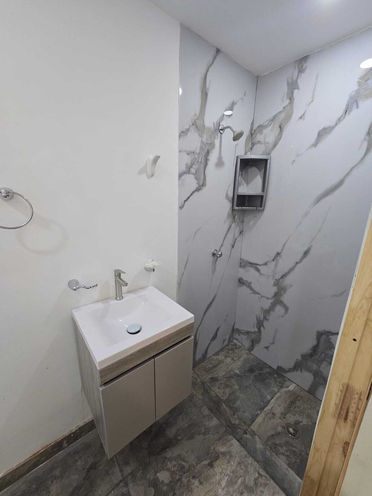 Une salle de bain avec un mur en marbre, un lavabo et une douche.