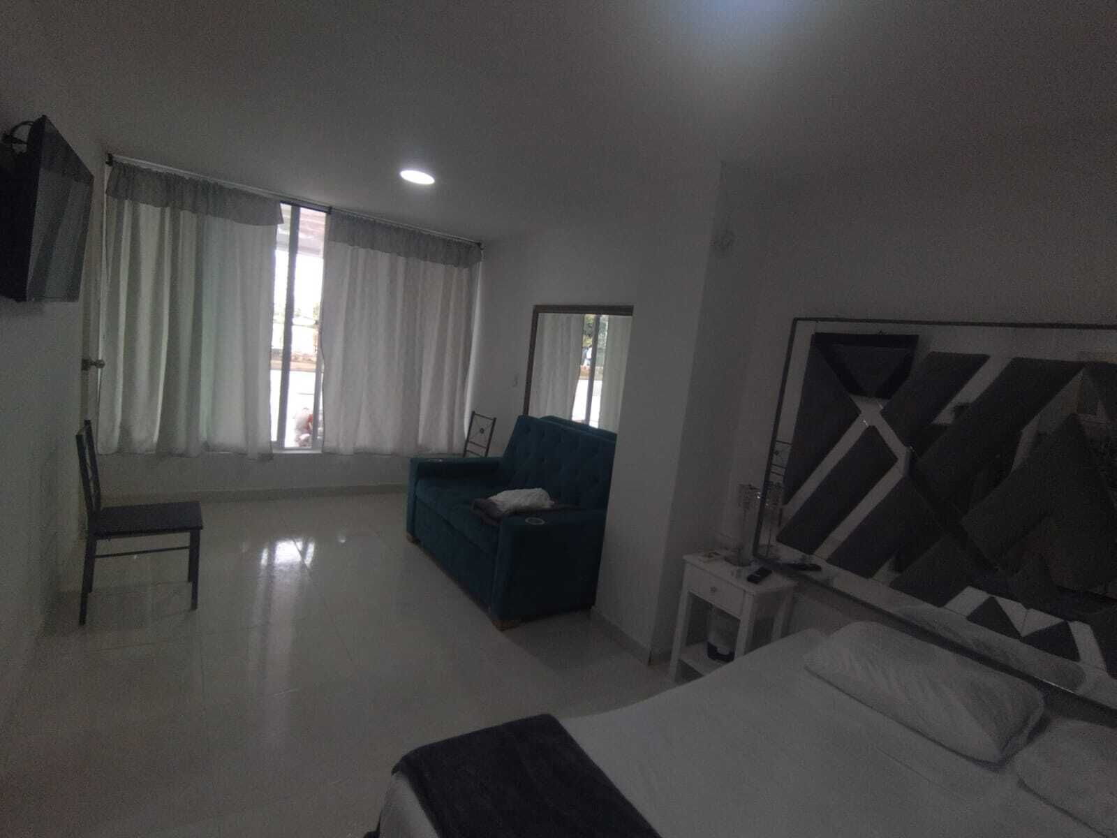 Una habitación de hotel con cama, un sofá azul, una silla y un escritorio con computadora.