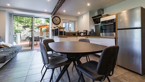 Une cuisine moderne avec un coin repas, de grandes fenêtres et un four encastré.