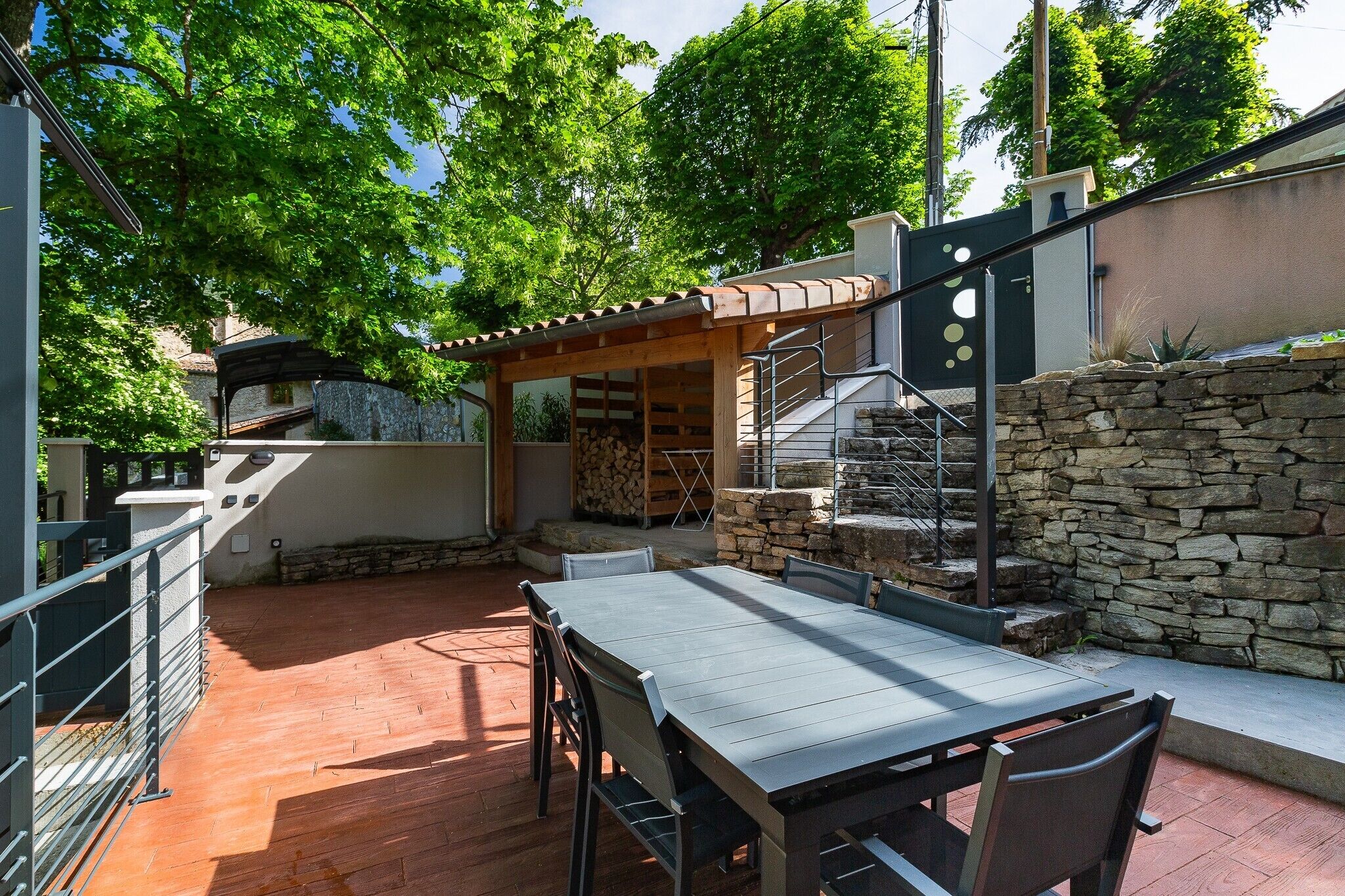 Un patio con tavolo e sedie, un muro in pietra e un pergolato.