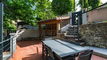 Un patio con tavolo e sedie, un muro in pietra e un pergolato.