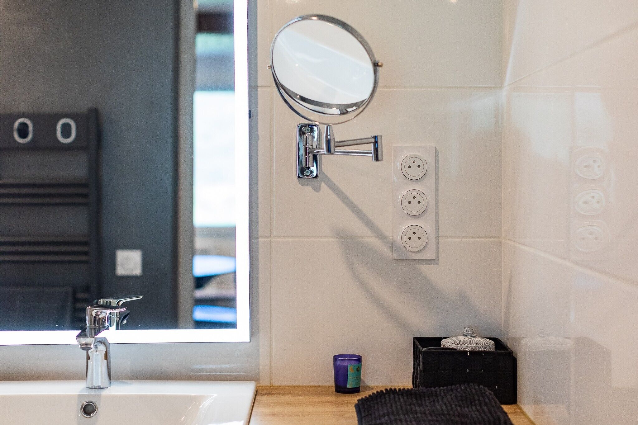 A bathroom with a sink, mirror, and wall-mounted electrical outlets.