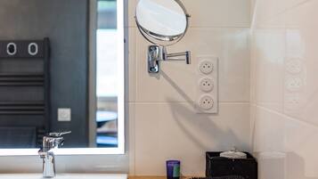 A bathroom with a sink, mirror, and wall-mounted electrical outlets.