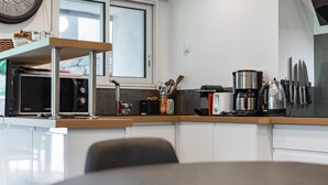 Une cuisine moderne équipée d’un four à micro-ondes, d’une machine à café et d’ustensiles de cuisine, le tout posé sur le plan de travail.