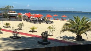 A beachside area with red umbrellas, lounge chairs, and a sandy path.
