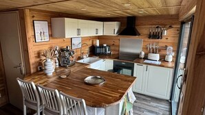 A compact kitchen with wooden cabinetry, a central island with seating, and modern appliances.