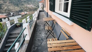 A balcony with wooden benches and a view of a mountainous landscape. - Ocean View Guest House (Sao Vicente)