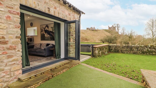 Un edificio de piedra con puerta de cristal que da a un salón con sofá y un cuadro.