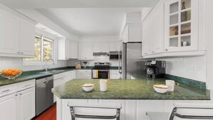 A modern kitchen with white cabinetry, a green marble countertop, and stainless steel appliances. - Large Whole Home in Wine Country: Pool Hottub Sauna + Spacious Backyard & Nature (Prince Edward)