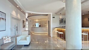 A modern hotel lobby with a reception desk, seating area, and a bar. - Amalfi Home – Relax near the sea with private beach and shuttle to Salerno (Pontecagnano)