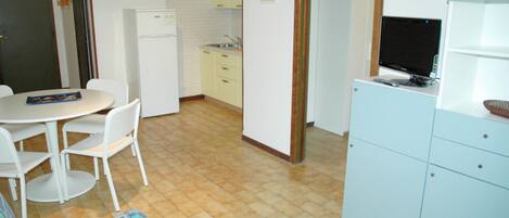 A compact kitchen with a refrigerator, sink, and a dining area with chairs.
