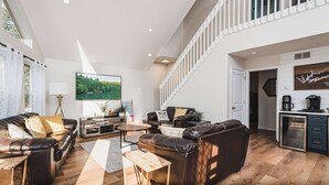 A spacious living area with a high ceiling, a staircase, and a kitchen area. - Lakefront Home w/Private Dock, Hot Tub (LaFollette)