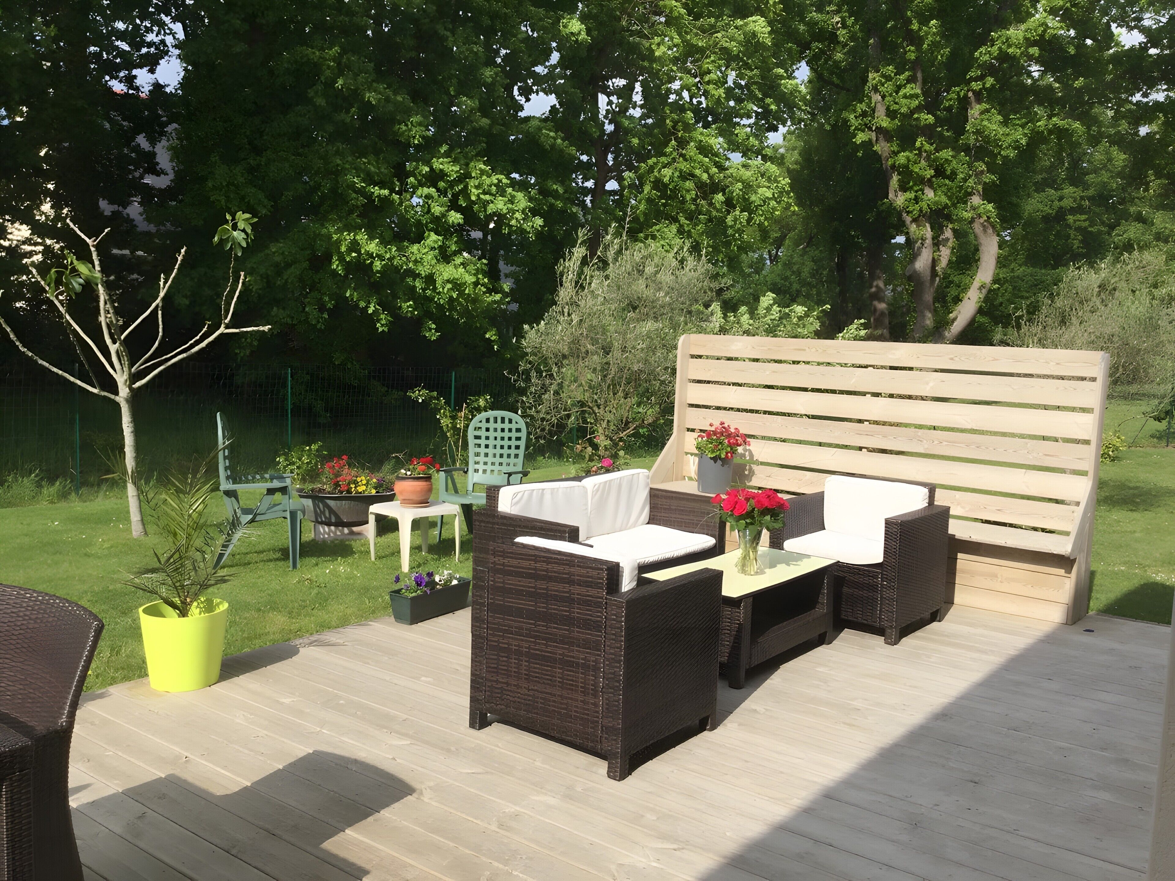 An outdoor patio with wicker furniture, a wooden bench, and potted plants.