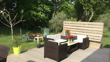 An outdoor patio with wicker furniture, a wooden bench, and potted plants.
