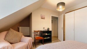 A bedroom with a bed, a chair, a bookshelf, and a door. - Bed and Breakfast 'Les Boubous-Nono' with Shared Terrace, Shared Garden and Wi-Fi (Saint-Nazaire)