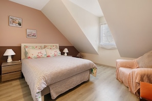 Un dormitorio con cama, mesita de noche, lámpara y ventana.
