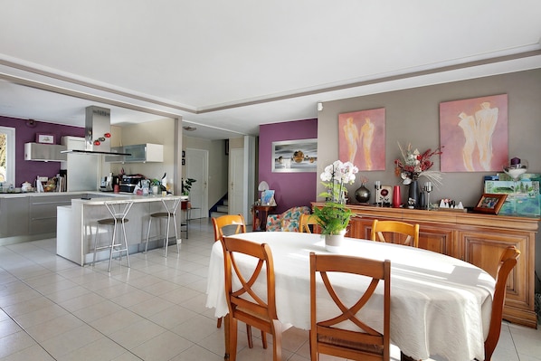 Una cocina moderna con comedor, que cuenta con una isla central, taburetes de bar y una mesa preparada para cuatro.