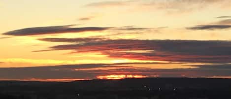Un coucher de soleil sur une ville, avec des bâtiments bien visibles et un ciel dégagé.