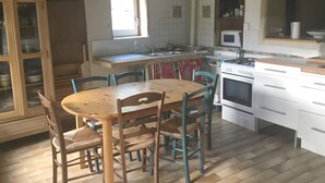 Una cuina amb taula i caires de fusta, fogó, microones i armaris.