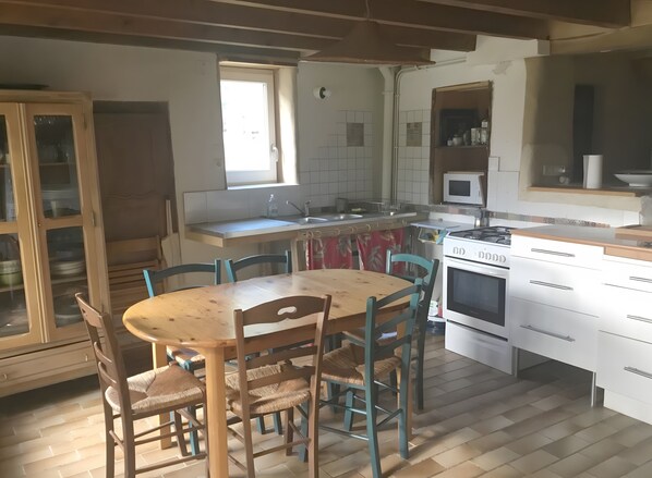 A kitchen with a wooden table and chairs, a stove, a microwave, and cabinets.