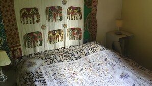 Una habitació amb un edredó estampat, un tapís mural i una làmpada de nit.
